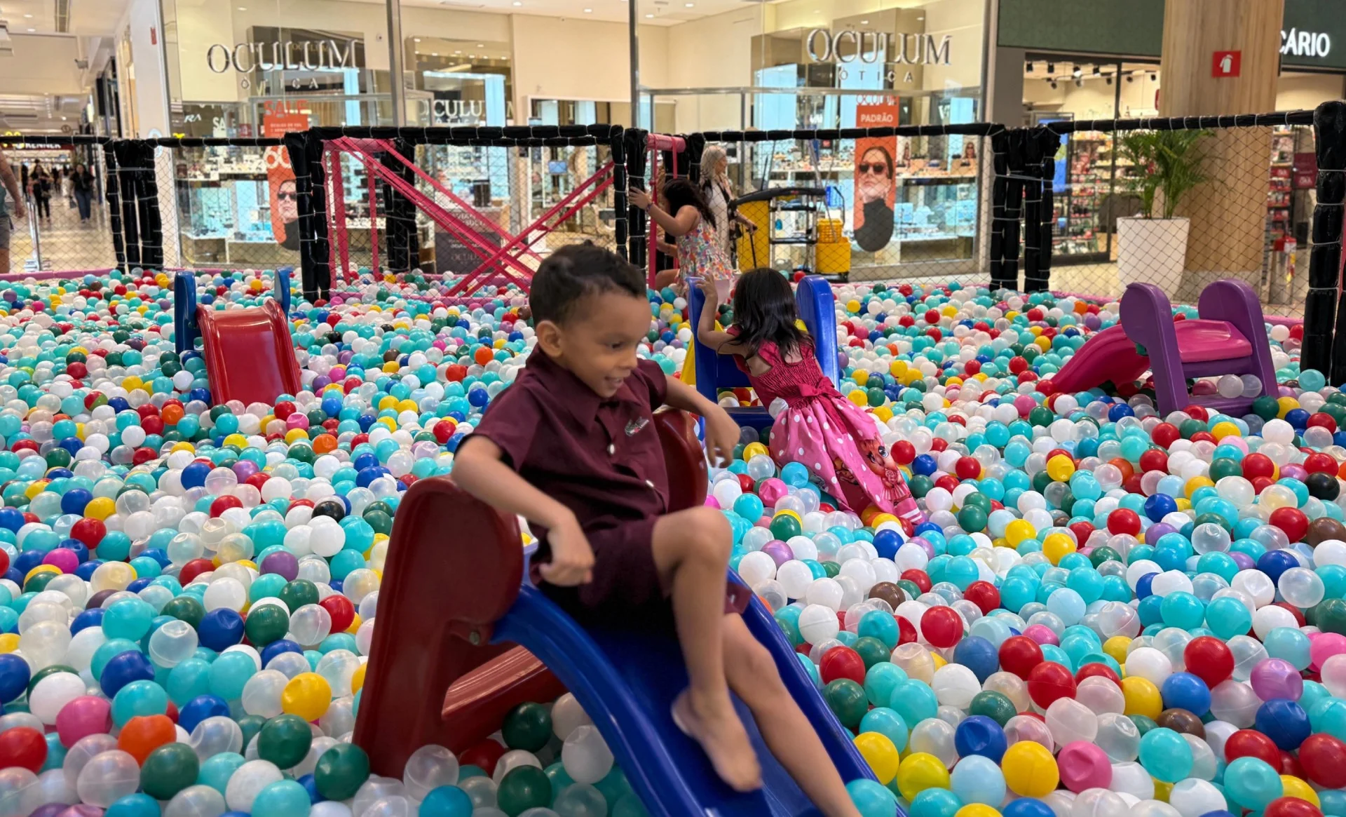 Criança no escorregador dentro de uma piscina de bolinhas